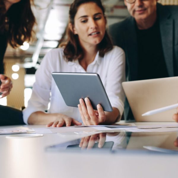 Businesswoman showing a digital tablet to her team and discussion work. Business people having a discussion during meeting over new project.